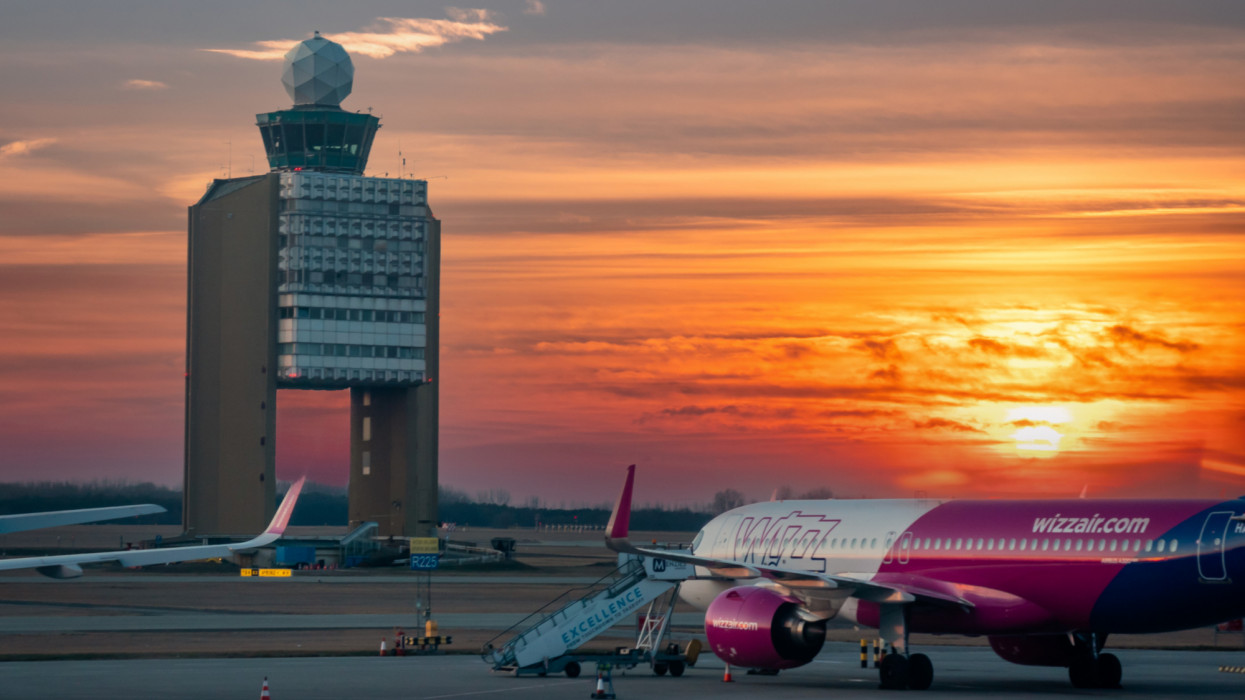 Budapest, Hungary - March 14, 2022: View of Budapest Airport Air Traffic Control Tower with Dramatic sunset with Wizzair planes on the runway