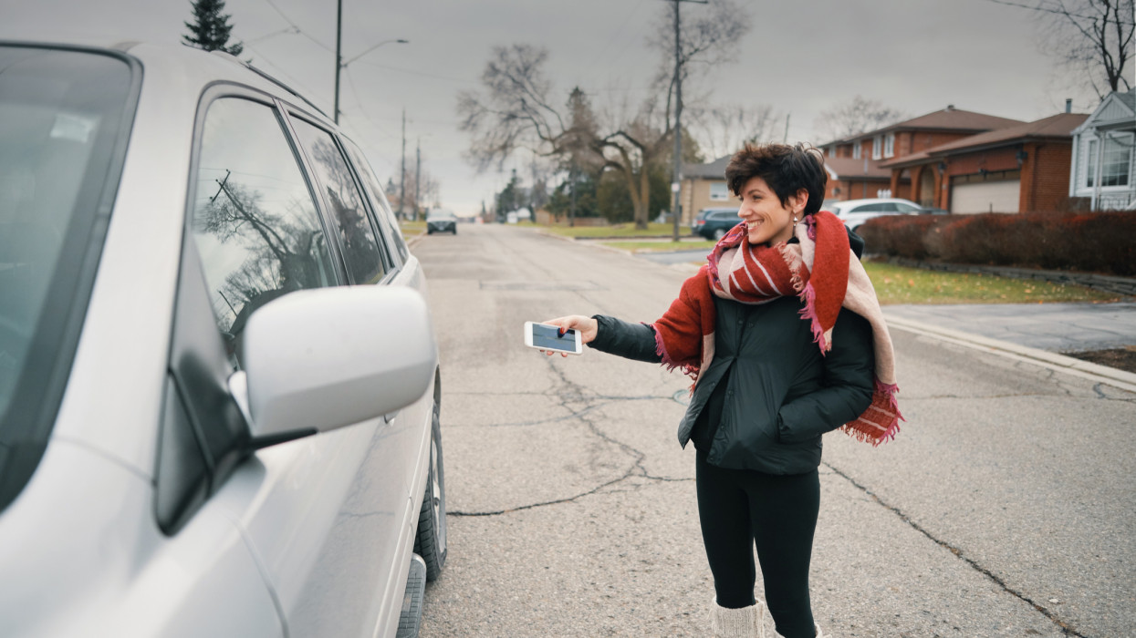 Woman opening her car with a smart phone