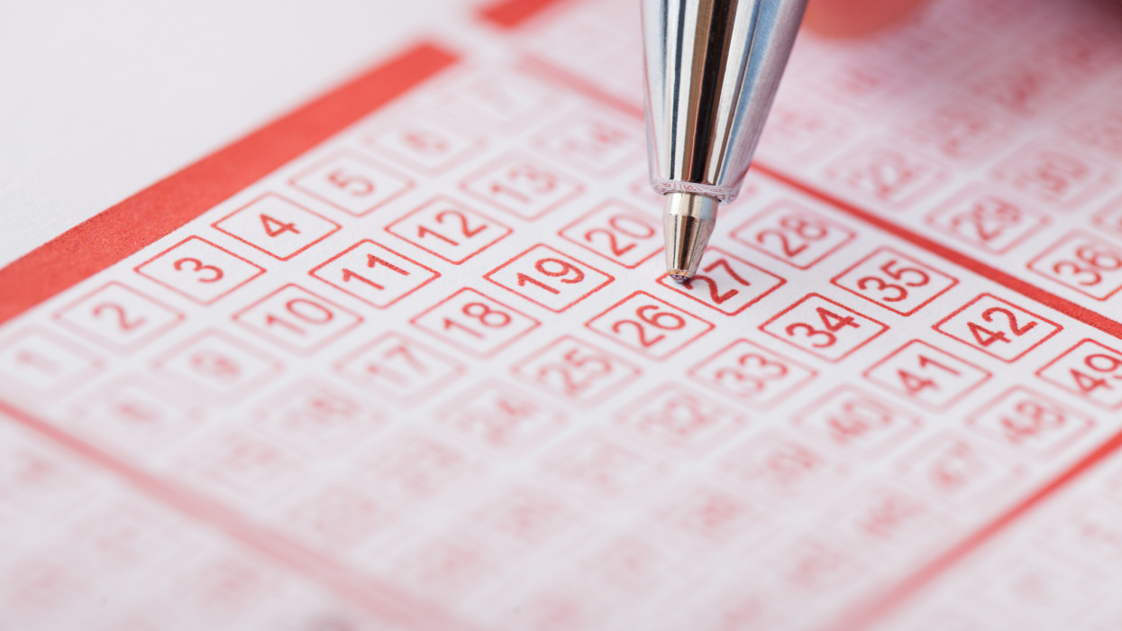 Close-up Of A Person Marking Number On Lottery Ticket With Pen