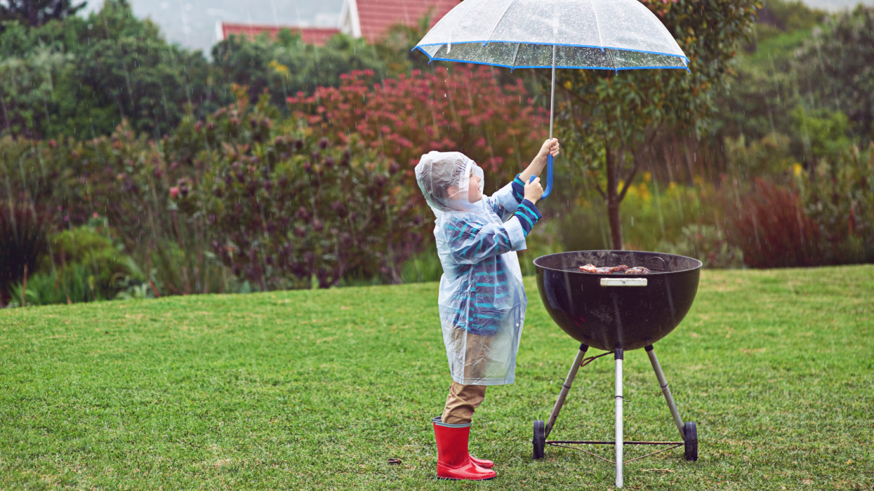 Full length shot of a young boy standing in front of an outdoor grill in the rainhttp://195.154.178.81/DATA/i_collage/pi/shoots/805690.jpg