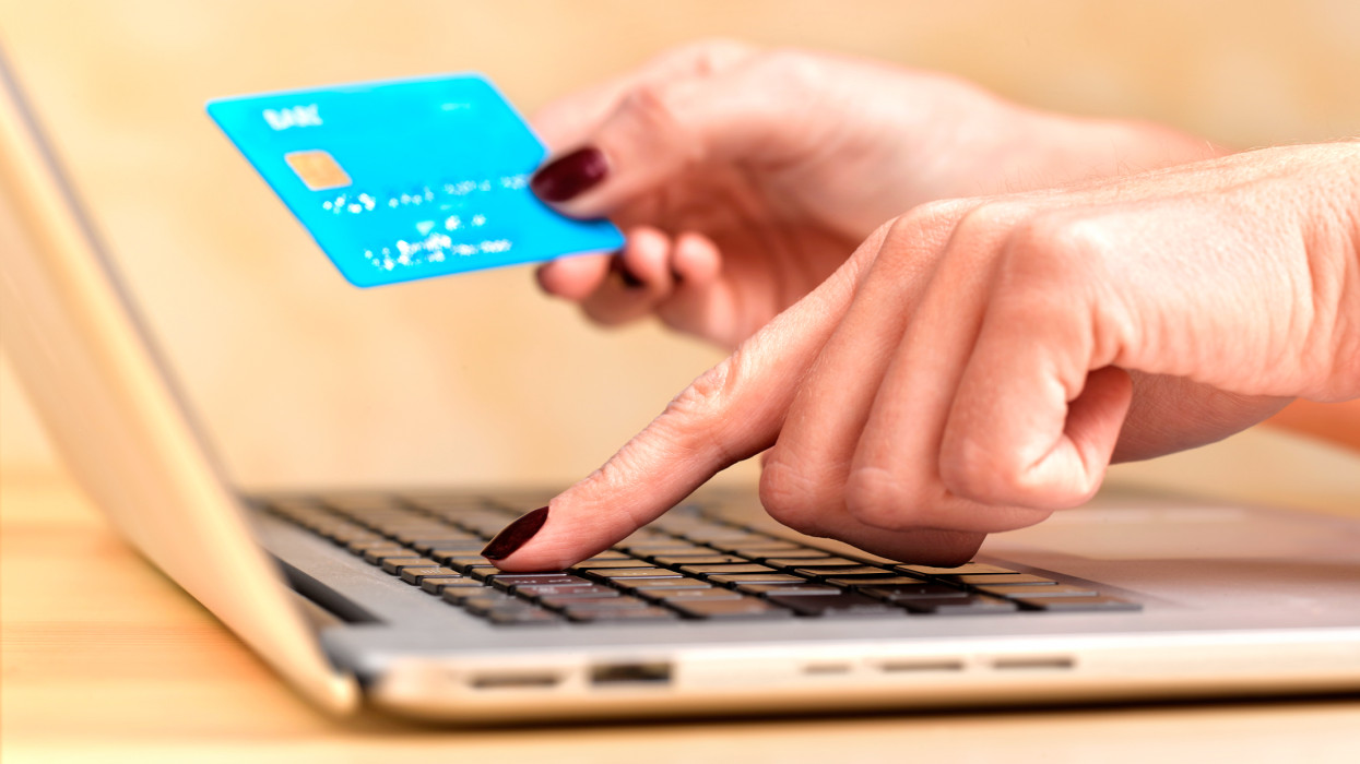 Close up of a woman at her laptop using a credit card to completer and online purchase