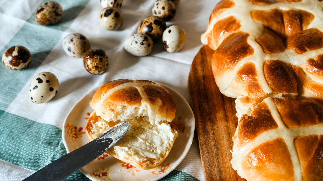 Easter homemade hot cross buns, buttered with butter, quail unpainted eggs. Easter family concept in Canada, Czech Republic, Germany, British, England.