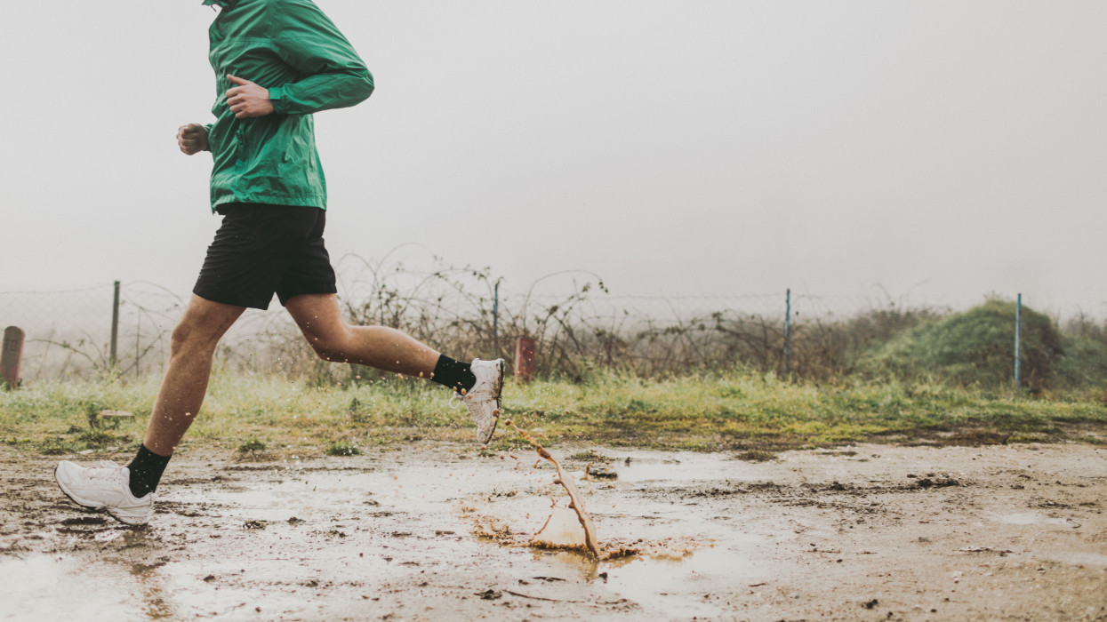 Photo of active man running in a cold, foggy, rainy morning
