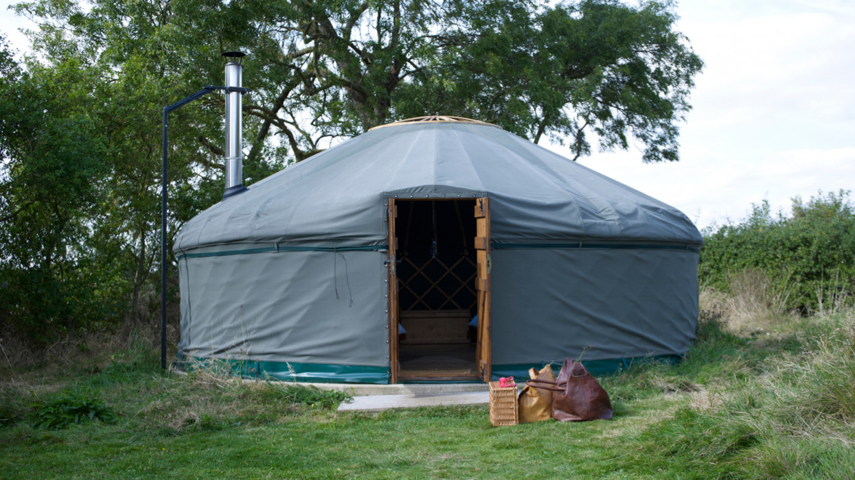 Open entrance to yurt on glamping site with packed bags in foreground.
