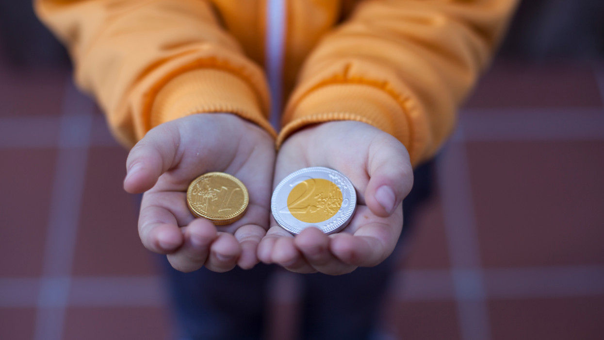 A childs hands showing two chocolate coins. The chocolate is the surprise of the day8 of the calendar of advent kid euro