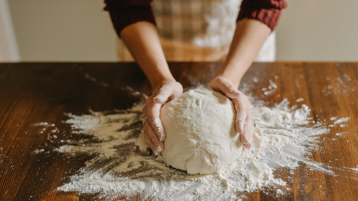Woman kneading bread dough. Close up of her hands touching the dough.