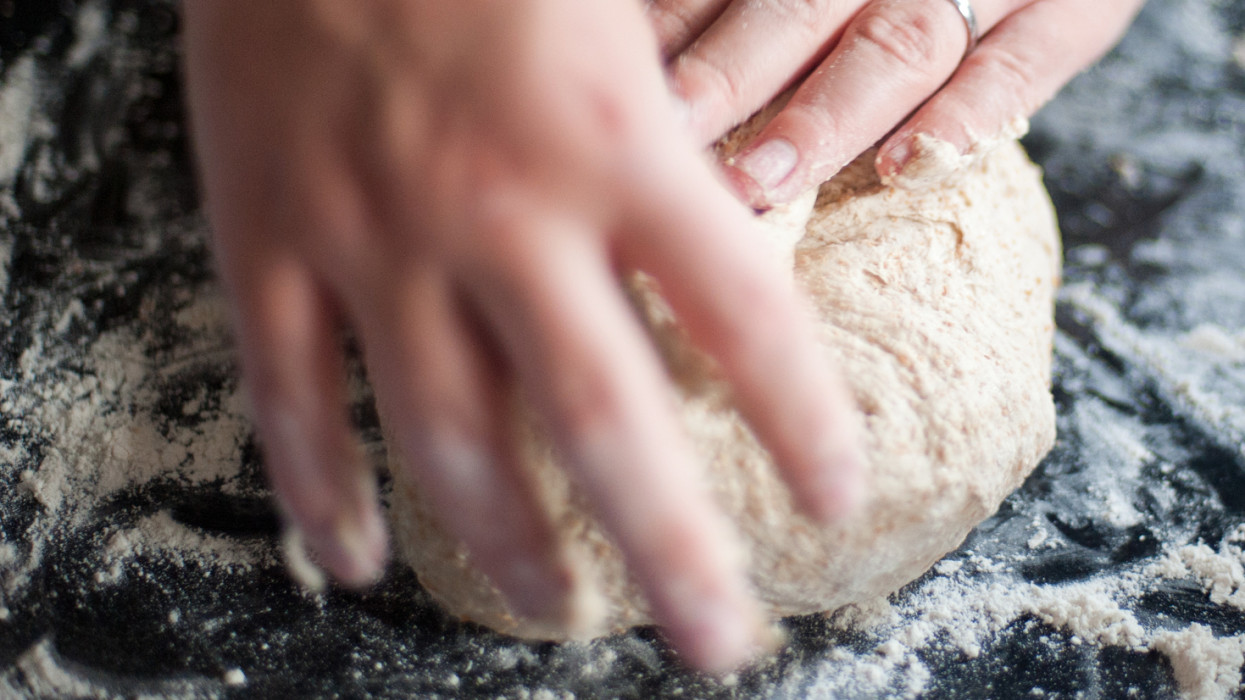 Man kneading bread dough on floured work surface