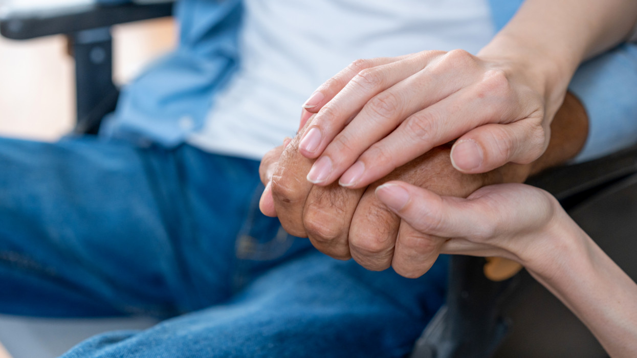 Nurse holding hands with elderly patient.