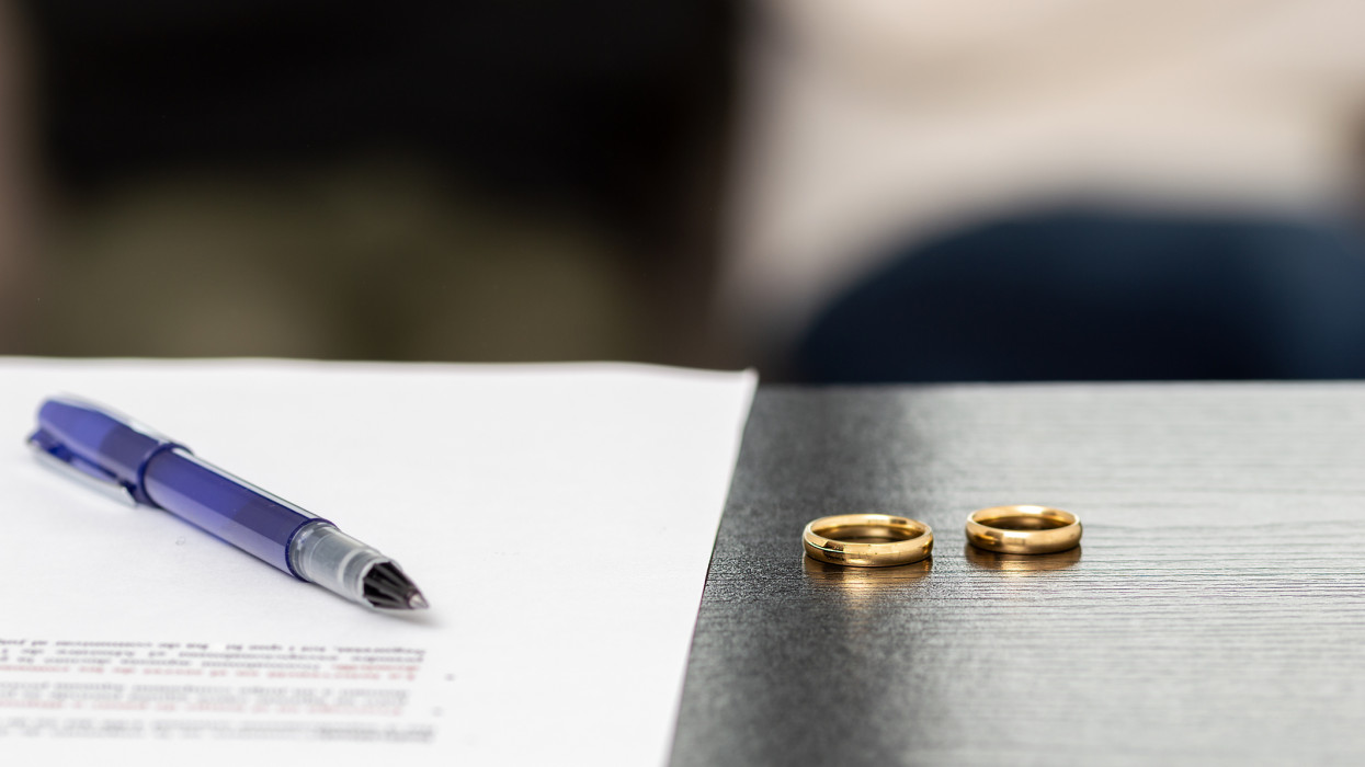 Document of a decree of divorce, dissolution, annulment of the marriage along with some wedding rings. Documents of legal separation, presentation of divorce papers or prenuptial agreement.