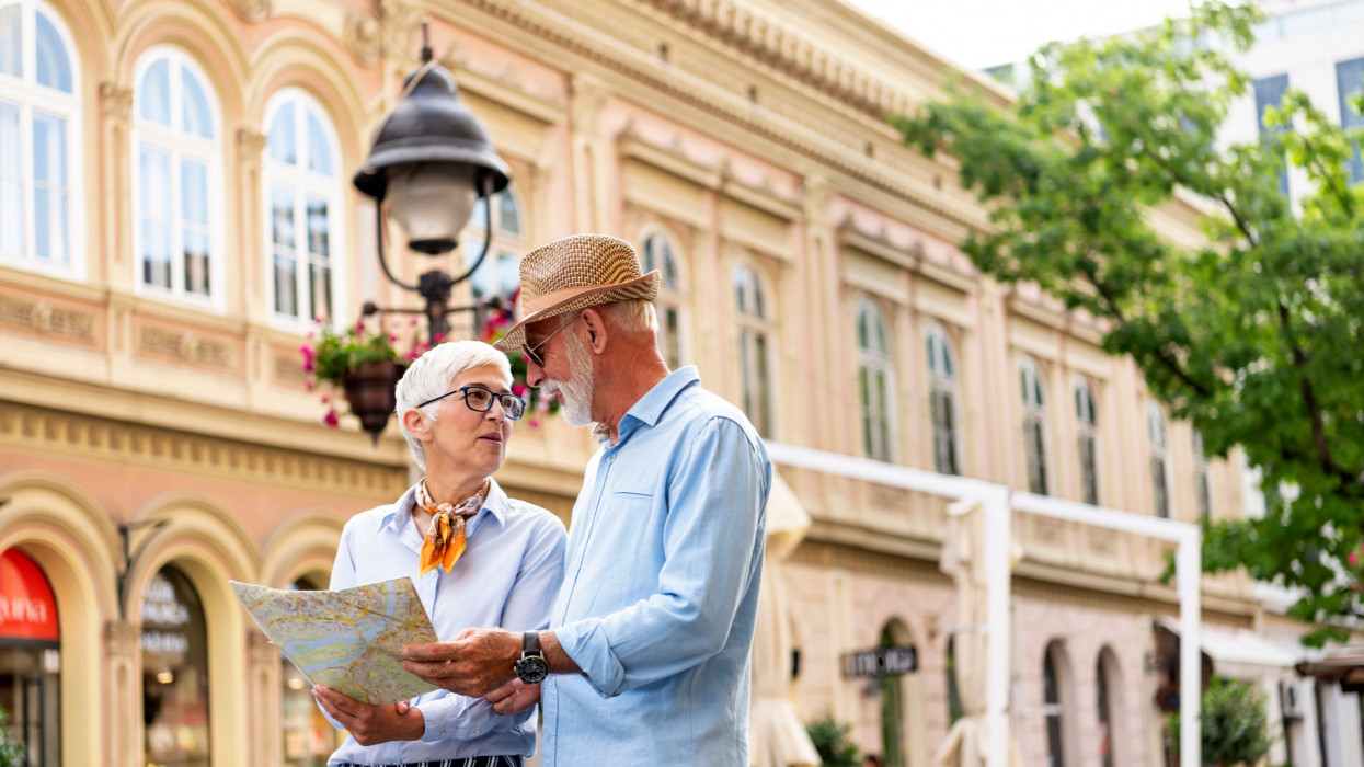 A Couple of Senior Tourists is Exploring the City. Handsome Bearded Man and his Beautiful Wife are Looking at the Map and Searching the City Sightseeings.