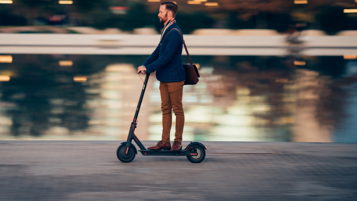 Profile view of businessman riding a scooter on his way to work