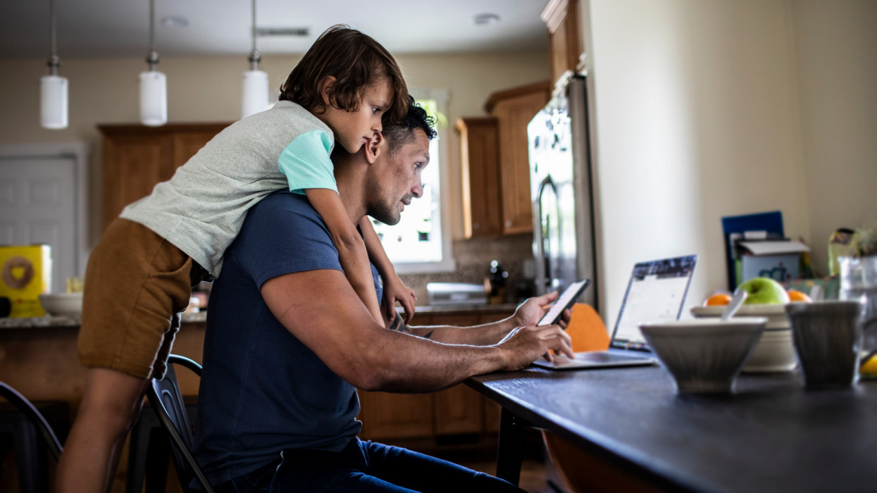Father using laptop while son looks over his shoulder