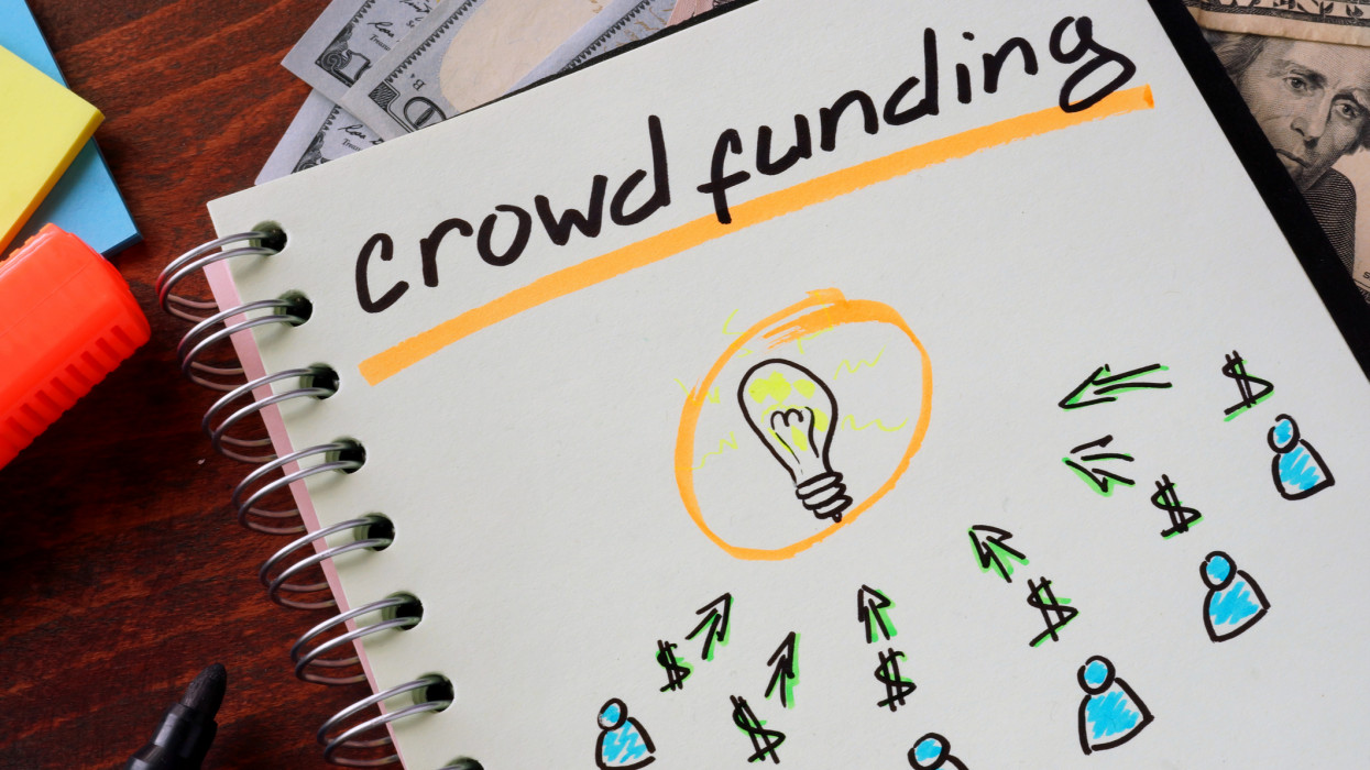 Notebook with crowd funding  sign on a table. Business concept.