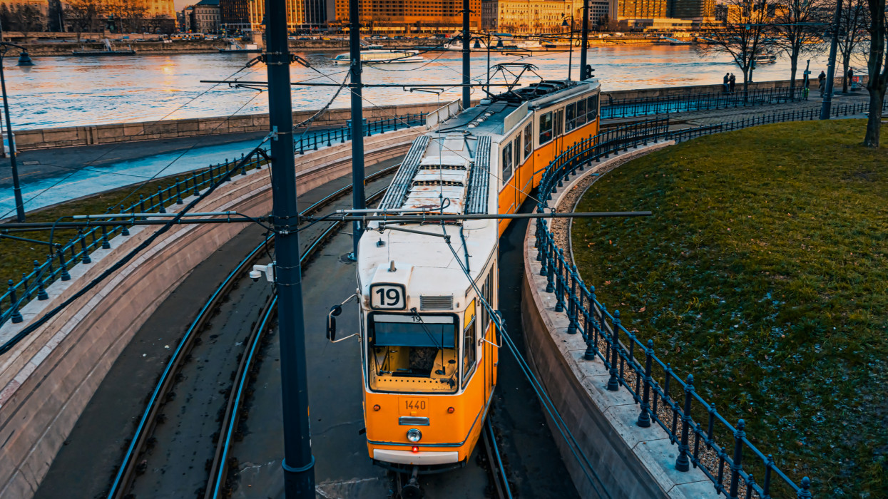 A yellow tram travels along the banks of the Danube. Sunset view.