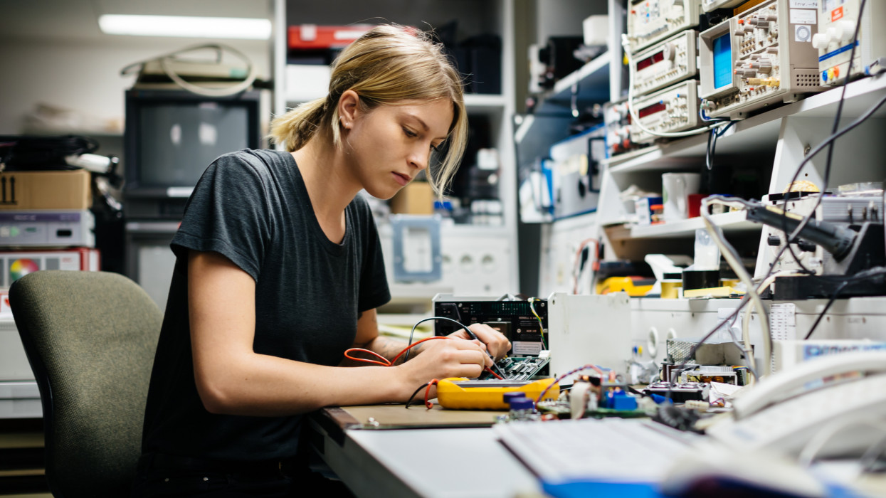 Young female engineer measuring voltage on a  conductor board in her workshop