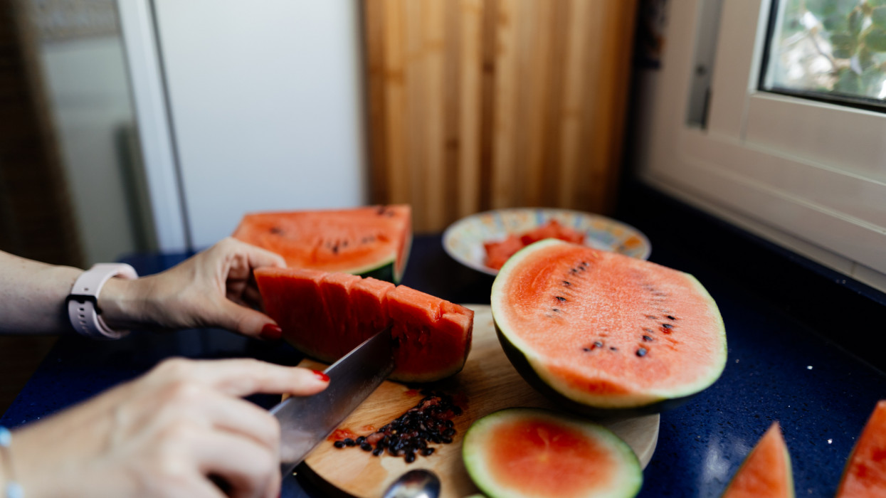 Woman hands removing watermelon seeds with a knife at home