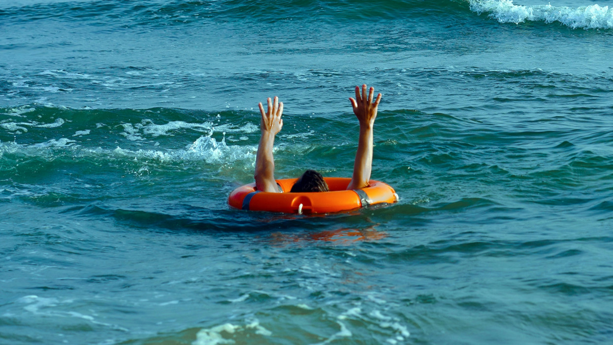 Lifebuoy for drowning man in sea or ocean water. Insurance concept. A man inside a lifebuoy at sea