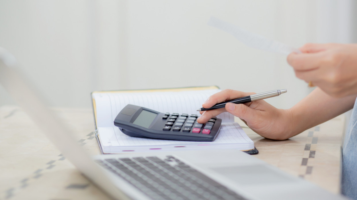 Closeup hands of woman calculating finance household with calculator on desk at home, girl checking bill for saving and planning expenses, debt and loan, tax and accounting, business and financial.