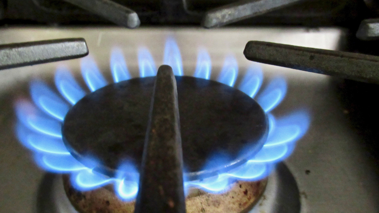 Close-up viewpoint of a natural gas stovetop with a blue flame evenly lit rising from a stove burner.