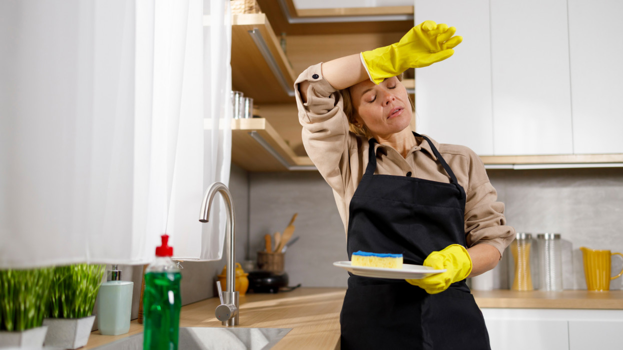 Tired of household chores woman washes dishes in the kitchen