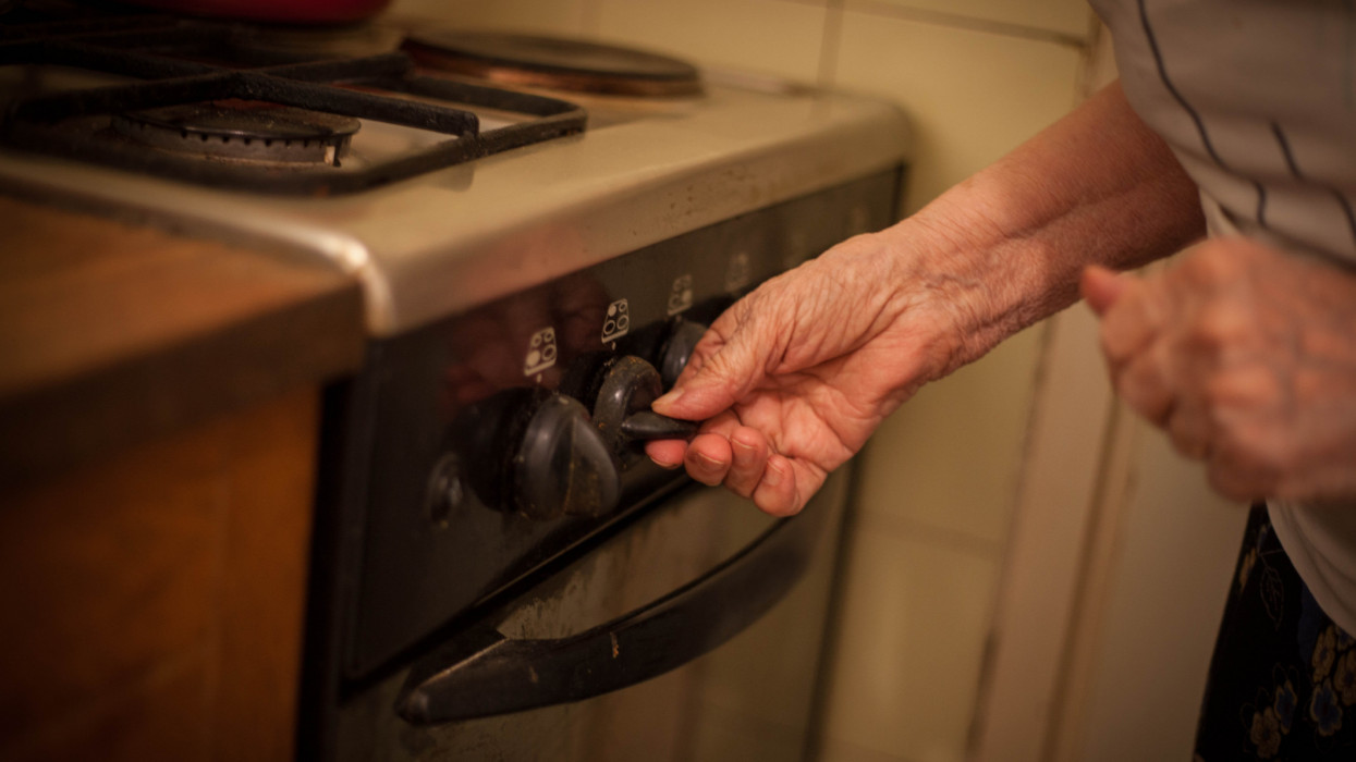 Close up of woman hands setting temperature. gas old senior lady stove cooking