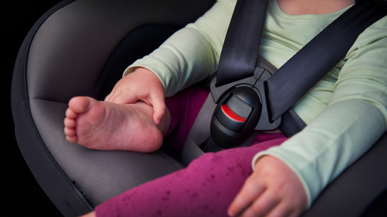 A mother fastening the buckle on a childâs car seat