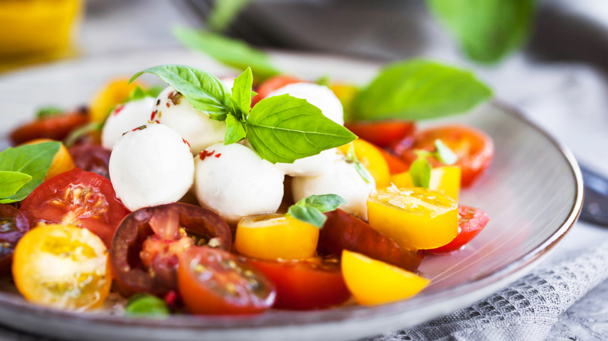 Fresh red and yellow cherry tomato salad with baby mozzarella cheese and basil, close-up