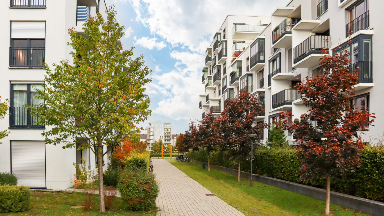 Cityscape with modern residential area, new apartment buildings and green courtyard with pavement and trees in autumn