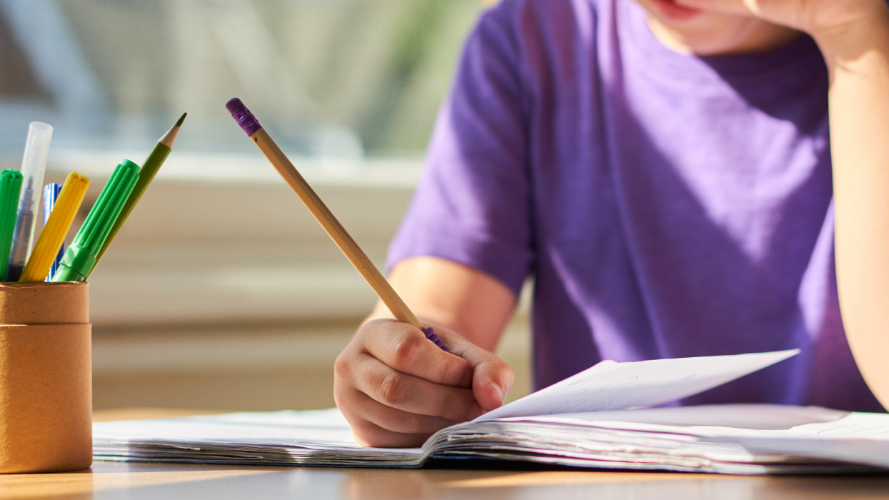 Young child sitting at a table learning and completing school work.