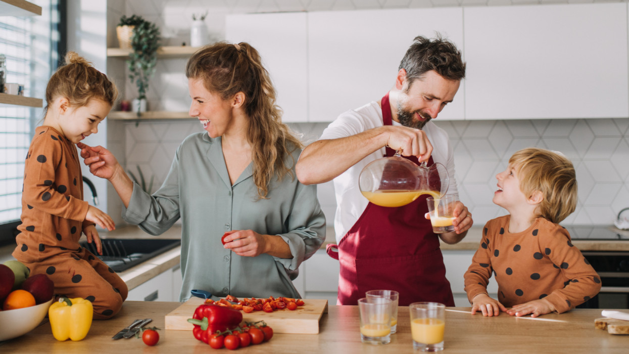 Cheerful parents with small children preparing food at home together. family breakfast kids