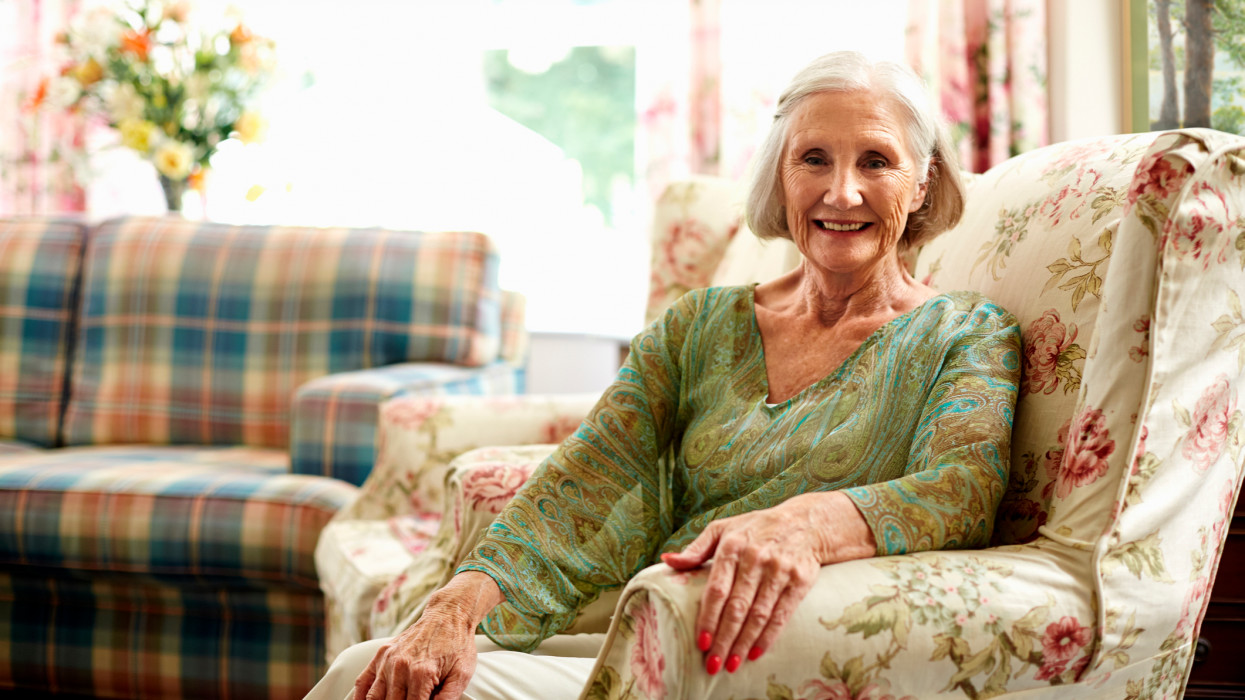 Portrait of happy senior woman relaxing on armchair in nursing home