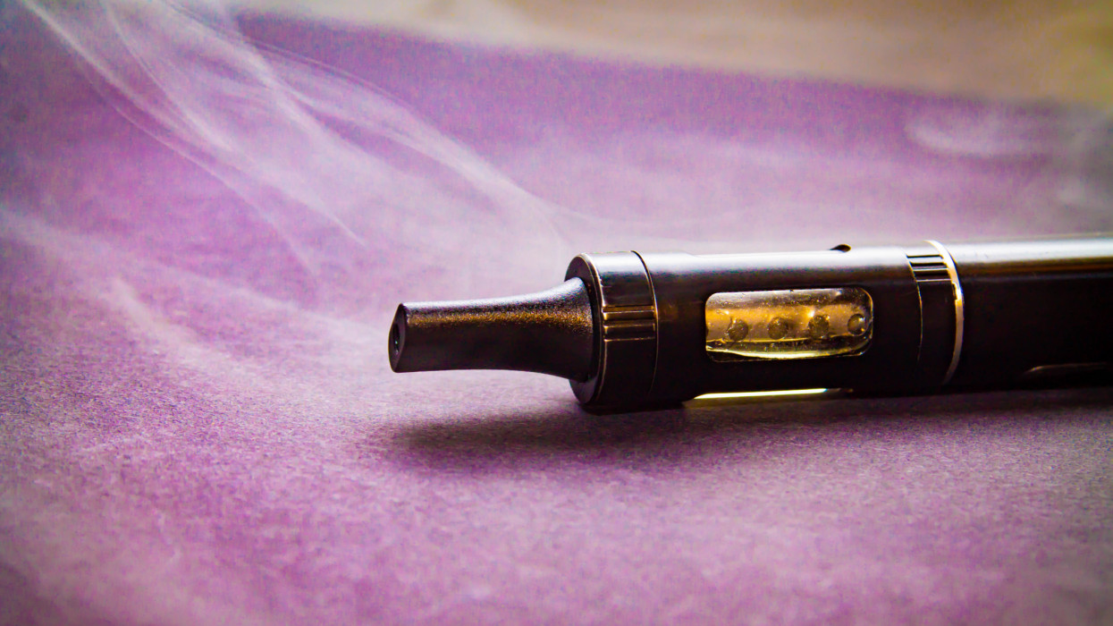 electronic cigarette in a light haze of smoke, vaporizer close on a stand on a purple background