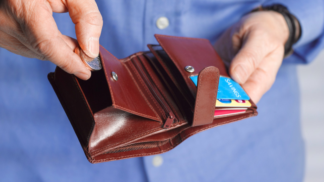Close up of a man with a wallet putting coins inside