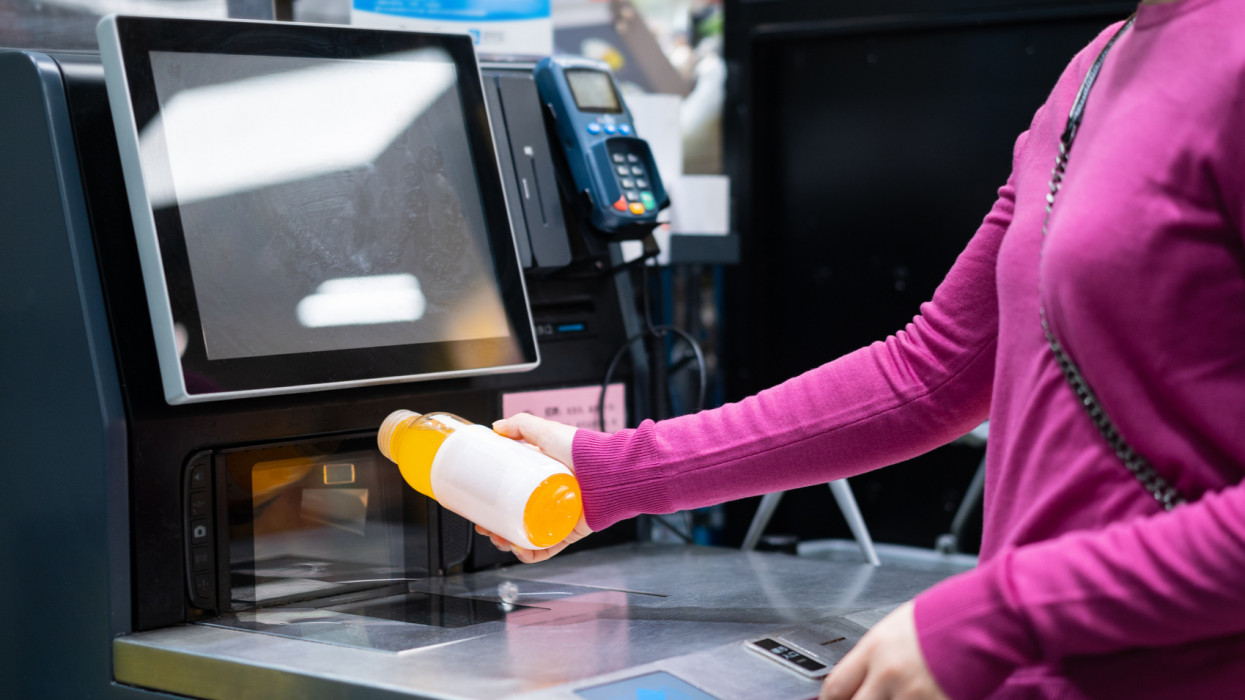 female checkout by automatic payment machine in supermarket