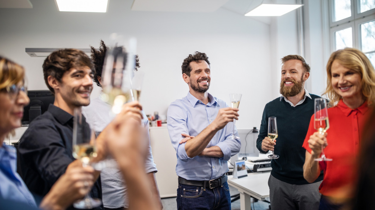 Happy male and female business professionals with champagne flutes during success party in office