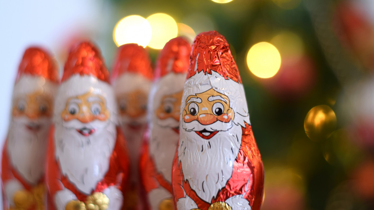 A lining of five Santa Clause shaped candies in front of the Christmas tree bokeh