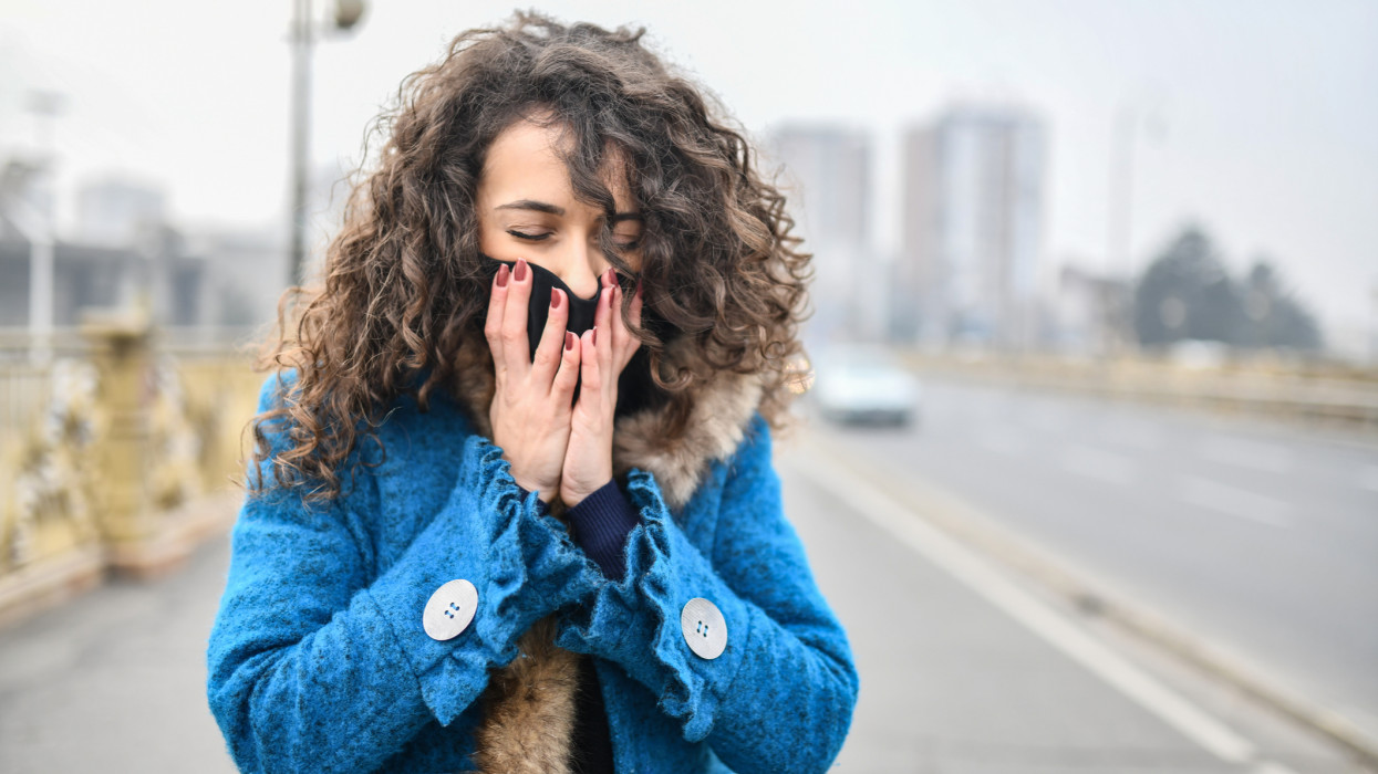 Female Struggling With Bad Air Pollution While Walking Through City