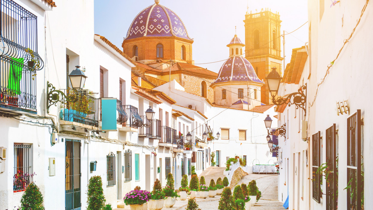 Bright image, vibrant colors narrow street of Altea and view to the blue-domed church of the Virgin de Consuelo. Altea is a town in the province of Alicante. Altea is a most beautiful place in the Costa Blanca. Spain