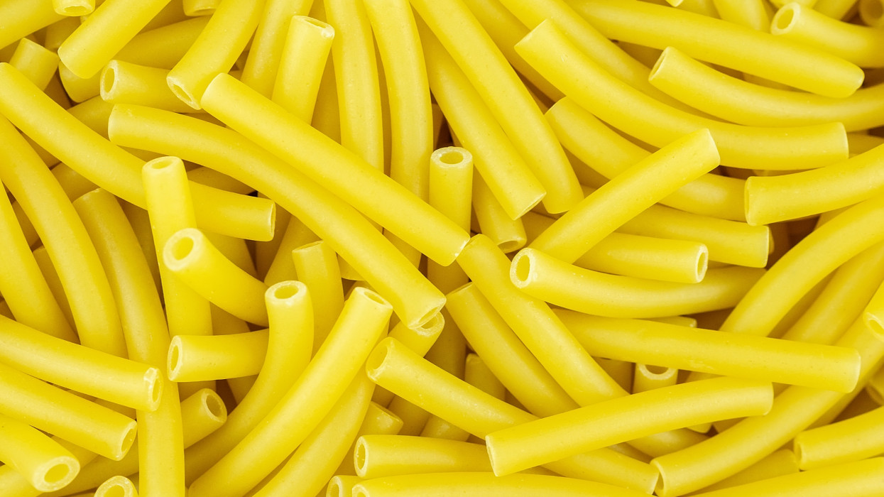 Background of scattered uncooked Italian maccheroni pasta shells