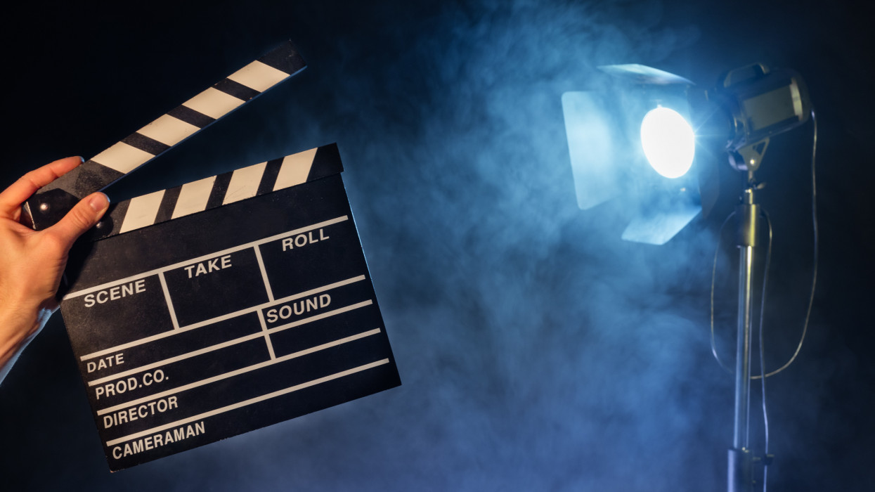 Operator holding clapperboard, studio light with claps on background. Filmmaker background