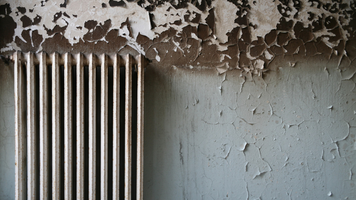 Radiator and wall with peeling paint in interior setting