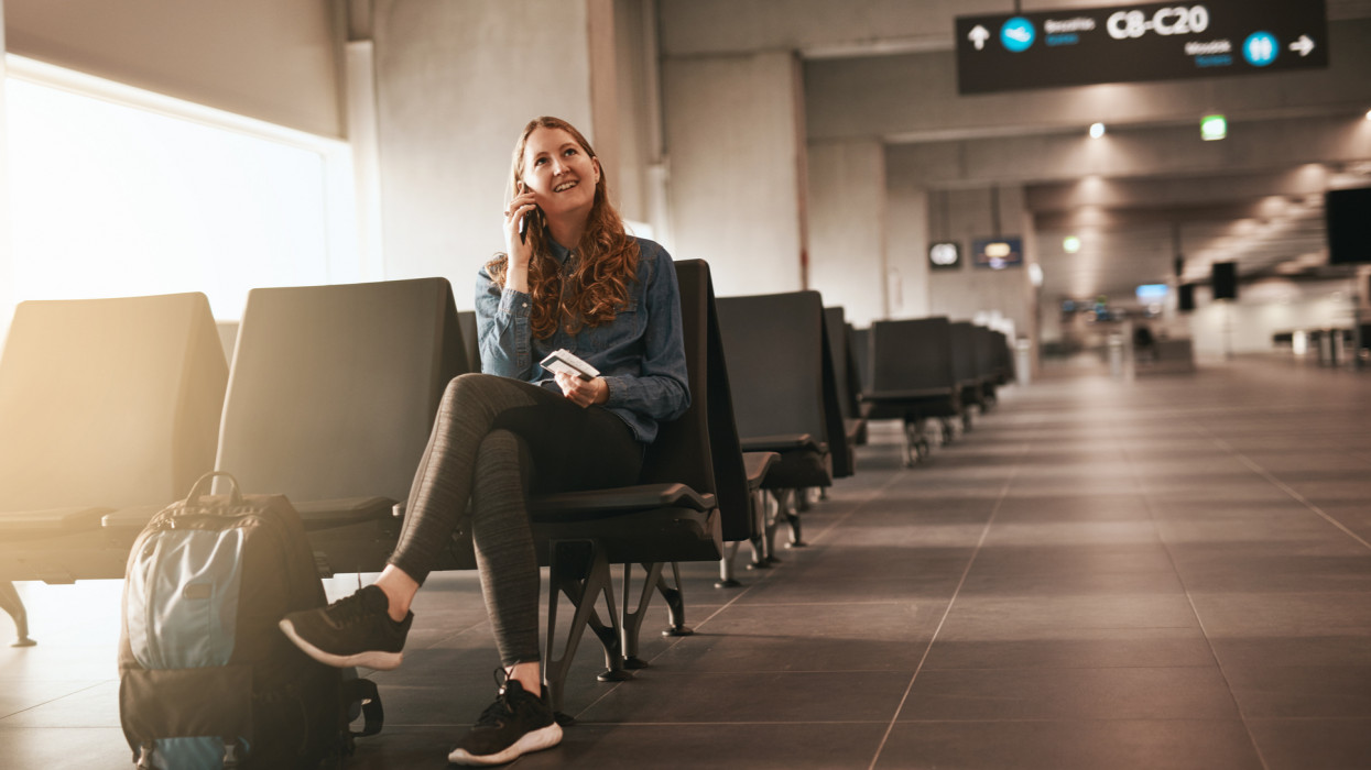 Shot of a young woman using her cellphone while sitting in the airport lounge area