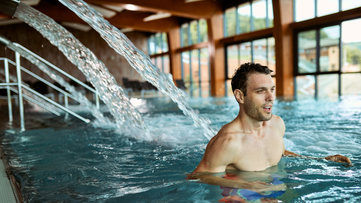 Mid adult man spending a day at wellness center and enjoying in a swimming pool.