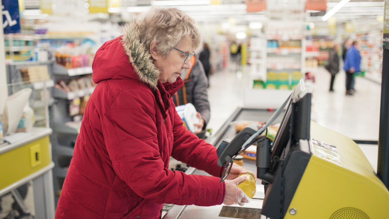 Senior woman using a self service checkout machine at a supermarket.