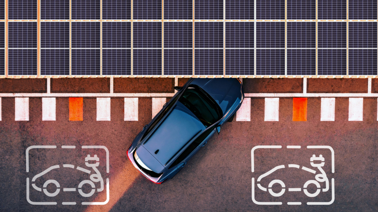 Directly above view taken with drone of a charging station for electric and hybrid cars using solar panels to generate electricity to charge cars battery while are parked in the city.