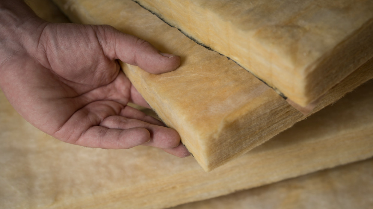 Hand holding a fiberglass batt. Image of home insulation.