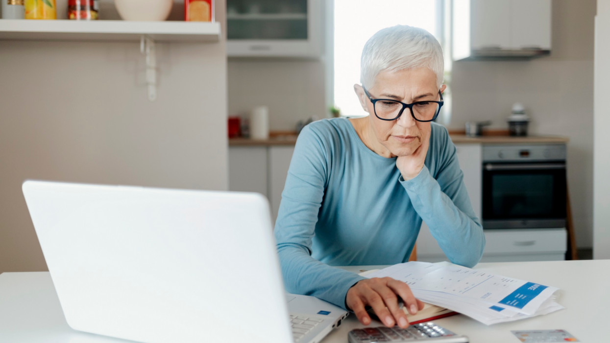Senior Mature Woman Analyzing Home Finances Managing Account Finance, Calculating Money Budget Tax, Planning Banking Loan Debt Pension Payment Sit at Home Kitchen Table.