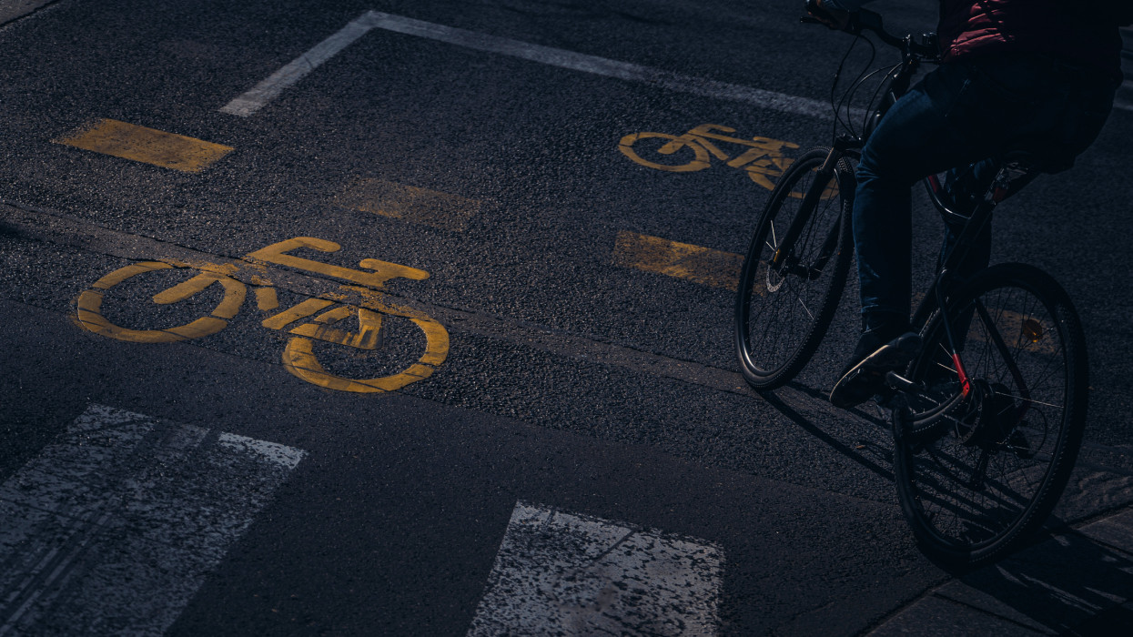 Unrecognisable person riding his bicycle along a cycle lane. In the picture we can see several drawings of a bicycle, painted on the road to indicate a bicycle lane. Image taken in the city of Budapest.