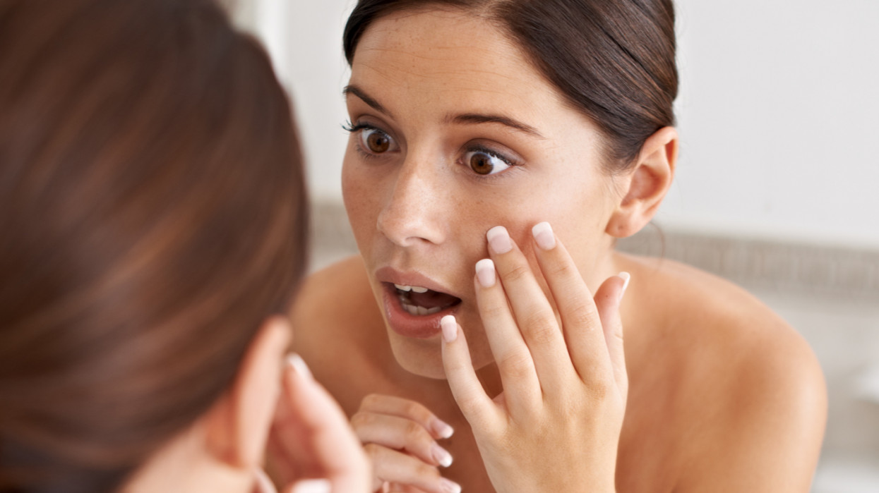 A young woman looking at a blemish in the mirror collagen skin