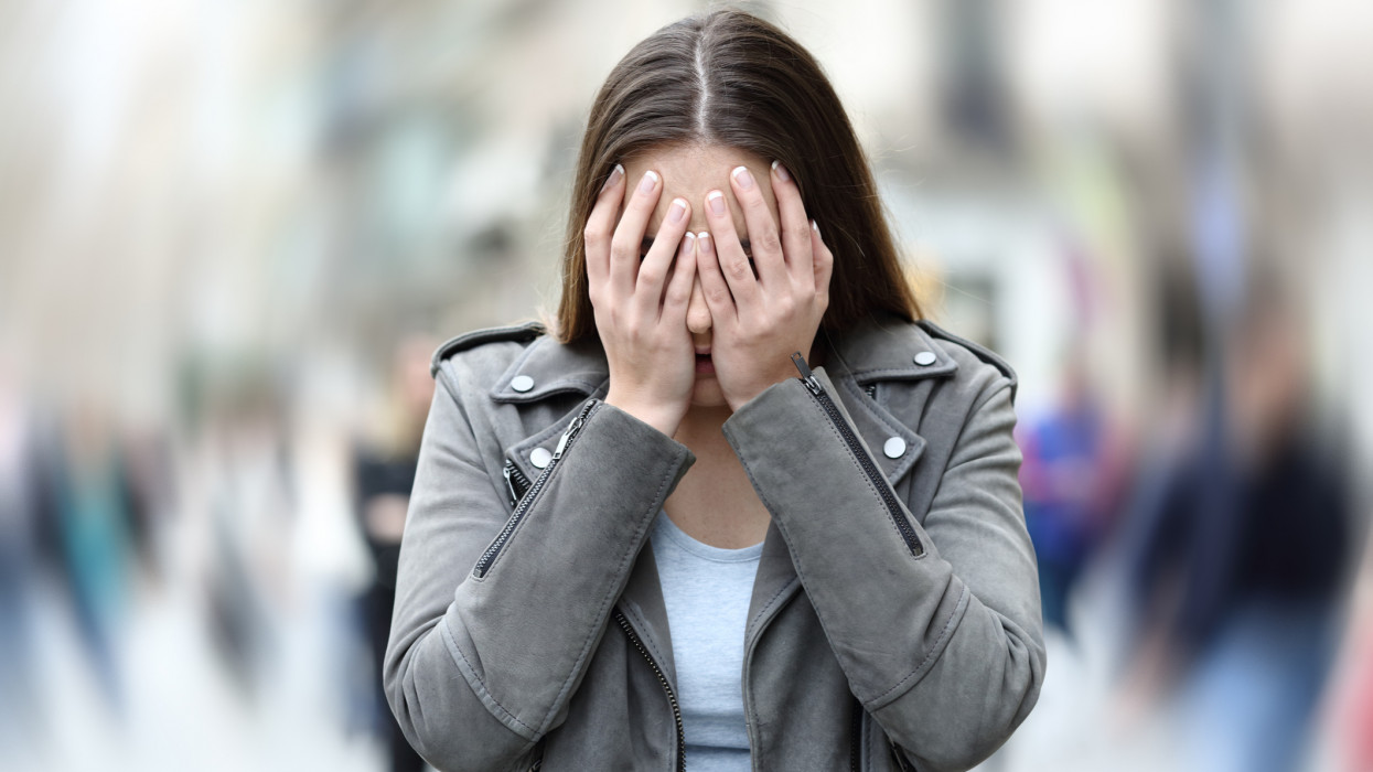 Front view of a woman suffering social anxiety attack on city street